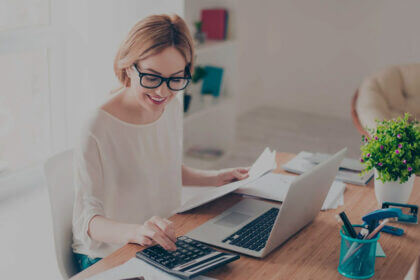 Small business owner outsourcing a bookkeeper working on laptop with financial reports and calculator on desk
