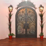 Front wrought iron doors with decorative scrollwork and glass panels installed on luxury home entrance