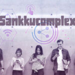 A group of five young people standing against a wall, all using their smartphones, with the word “Sankkucomplexh” displayed above them in bold letters.