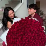 Andy and Michelle holding large bouquet of red roses celebrating their net worth success as social media couple